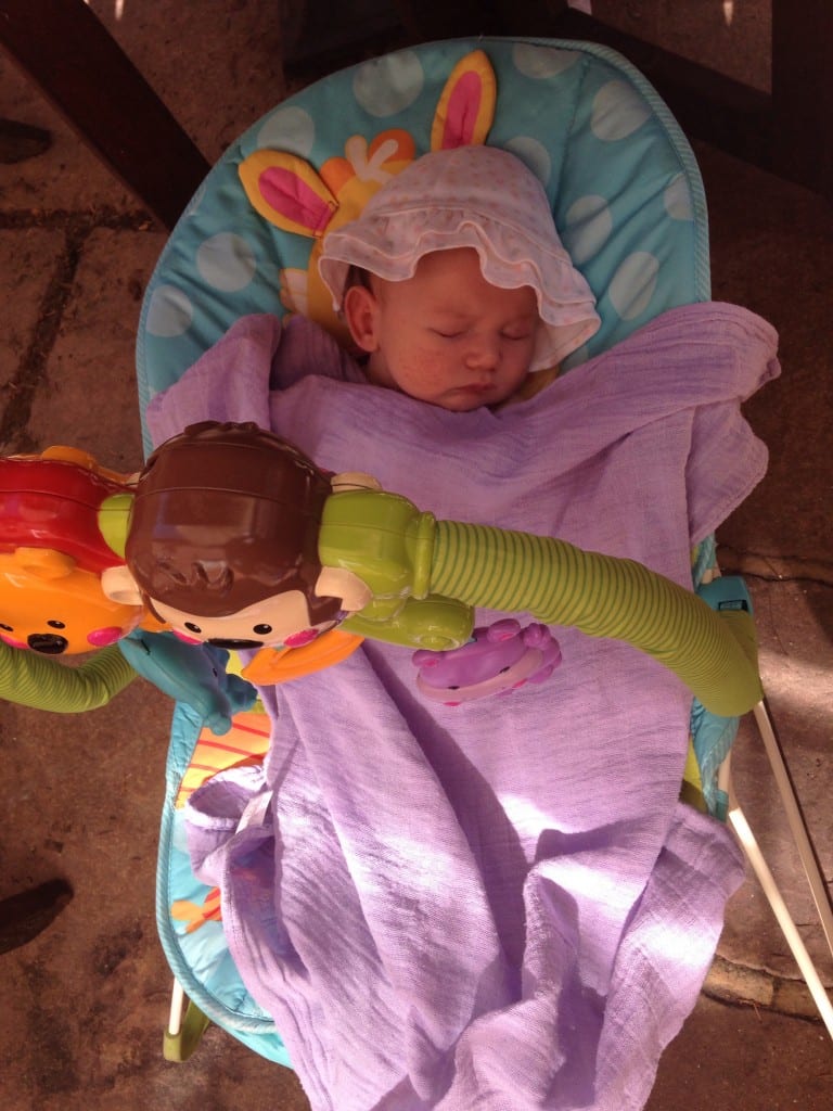 My Experience of A Cow’s Milk Protein Allergy (CMPA) Baby - picture of tiny baby in a floppy hat asleep in a baby bouncer