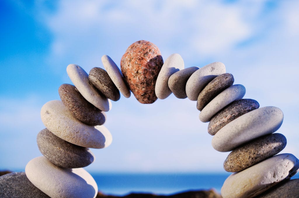 Meditation - rocks stacked in an arch and blue sky