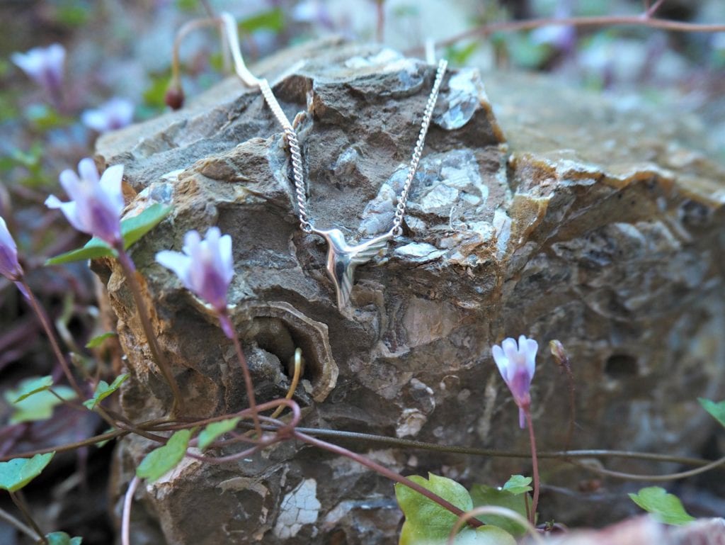 Jana Reinhardt Jewellery Review - necklace on a rock surrounded with small purple flowers