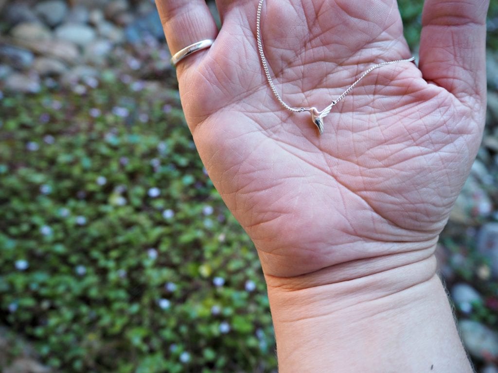 Jana Reinhardt hummingbird necklace on my hand