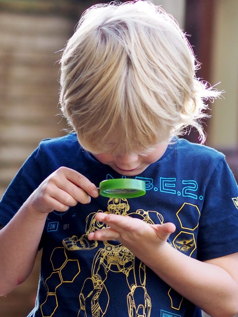 Logan looking at something in his hand with a magnifying glass