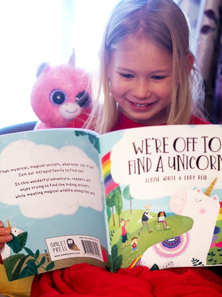 Aria and her unicorn teddy reading we're off to find a unicorn