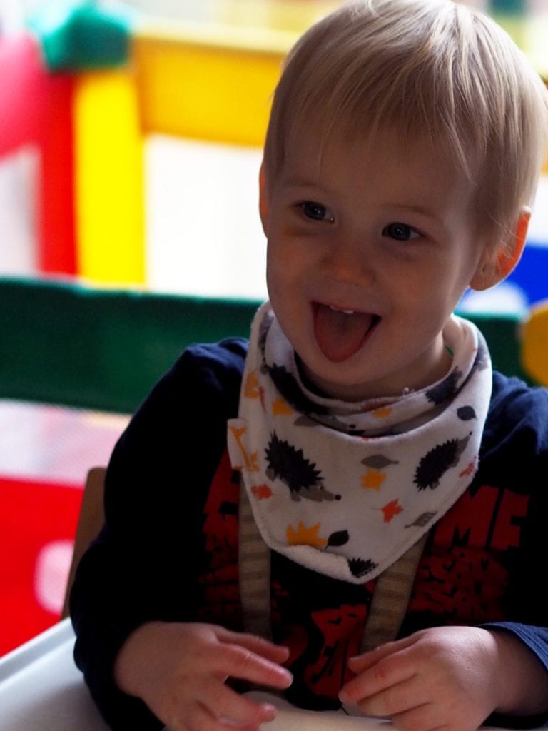 A picture of Bodhi in his highchair with a cheeky face sticking his tongue out