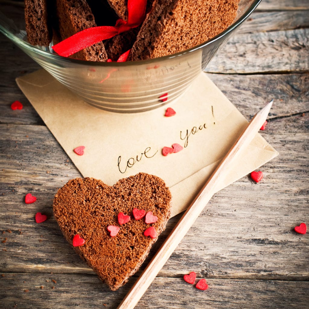 Eight Meaningful Things to do on Valentine's Day. Card with Message Love You in the Letter and Chocolate Cookies in the Shape of Heart at Valentine Day