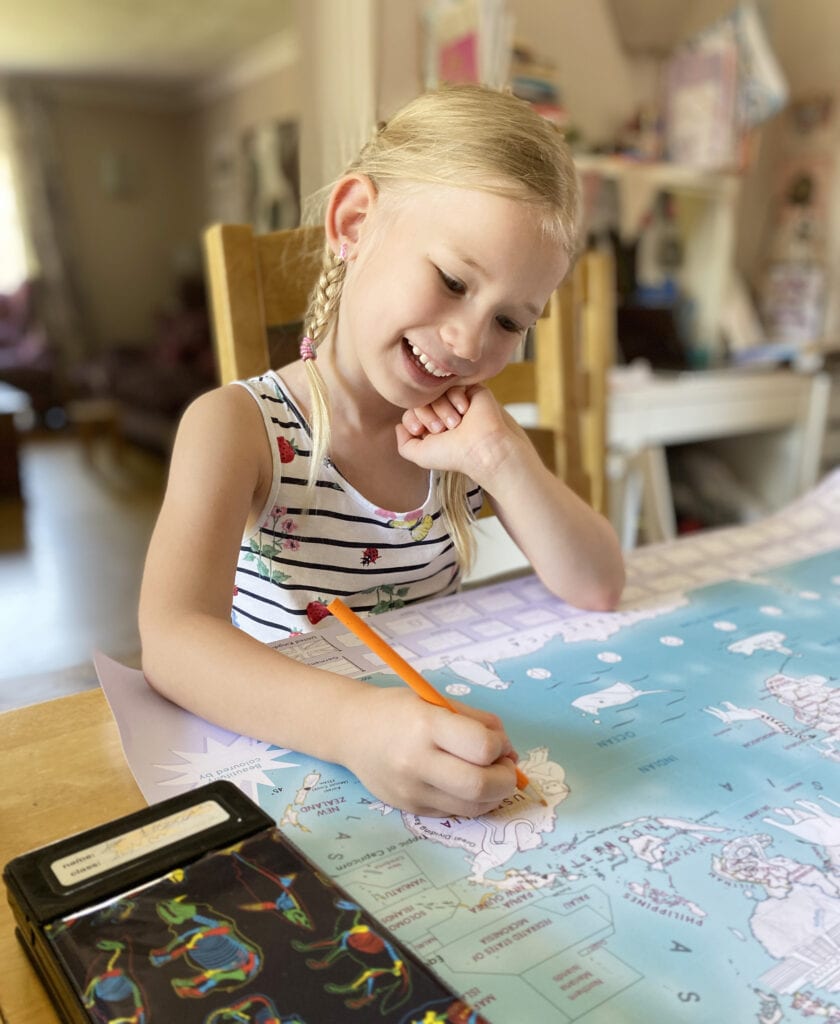 Aria sat at the dining table smiling and colouring large map