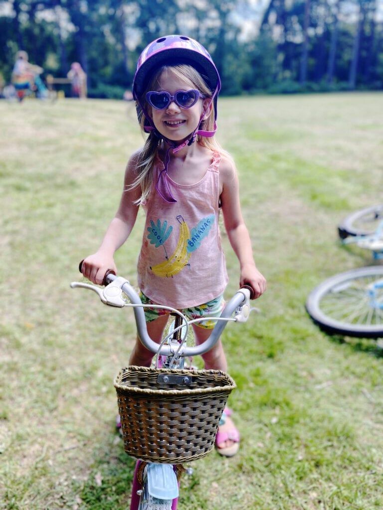 Aria on a bike with a cycle helmet and purple heart sunglasses