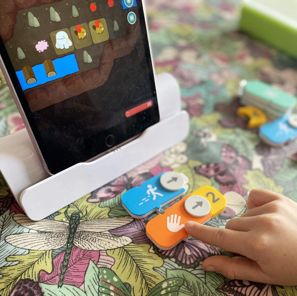 Picture of ipad with Osmo kit attached to it and a child connecting coding bricks together