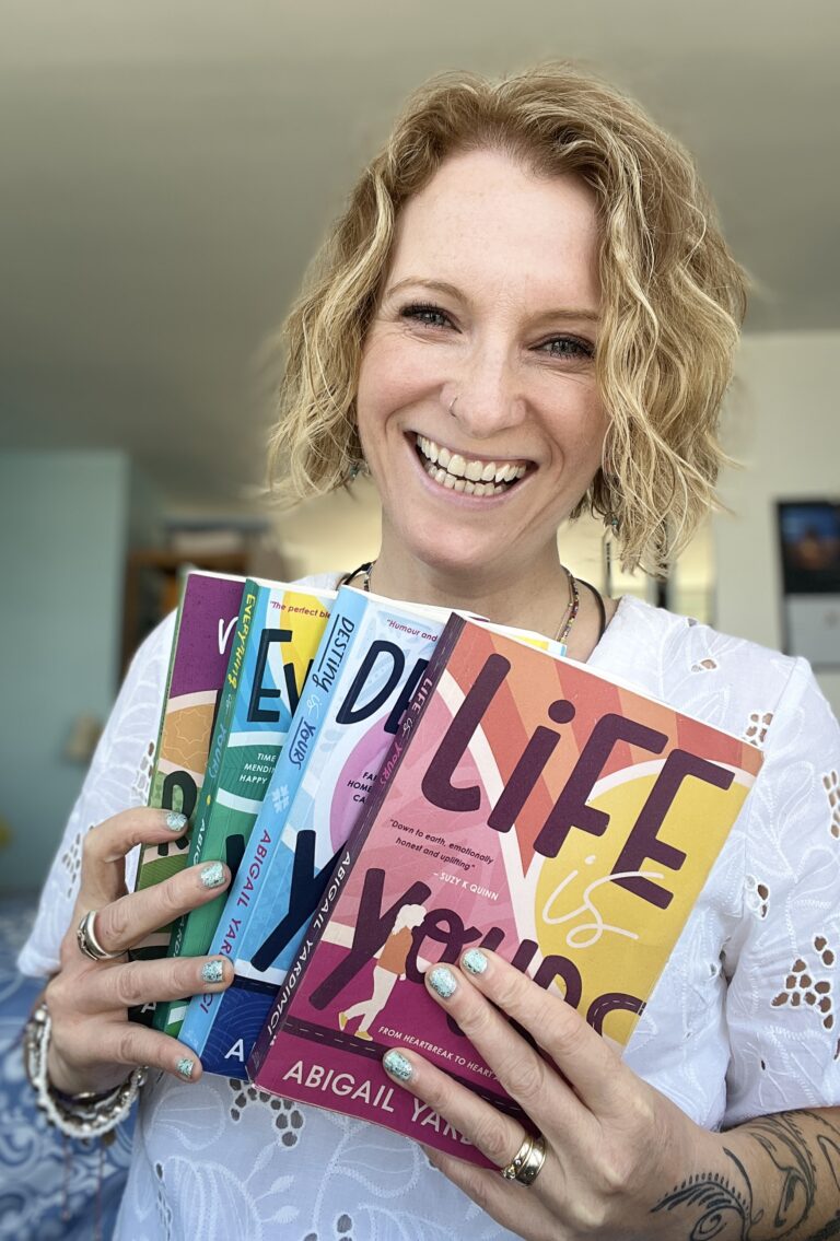 5 Self-Care Tips for the Summer by Abigail Yardimci. Picture of woman with blonde curly hair holding up 4 books