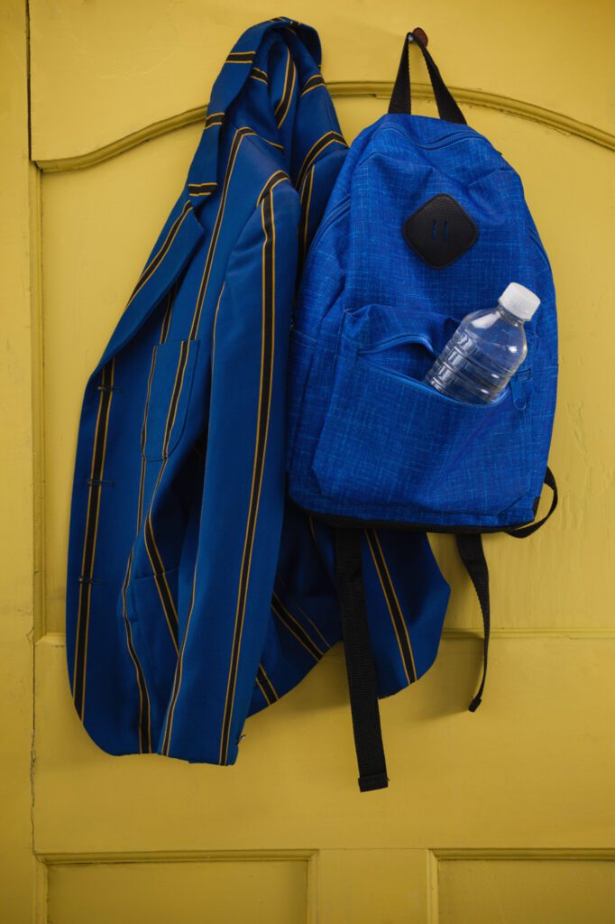 Close-up of school uniform and bag hanging on yellow door